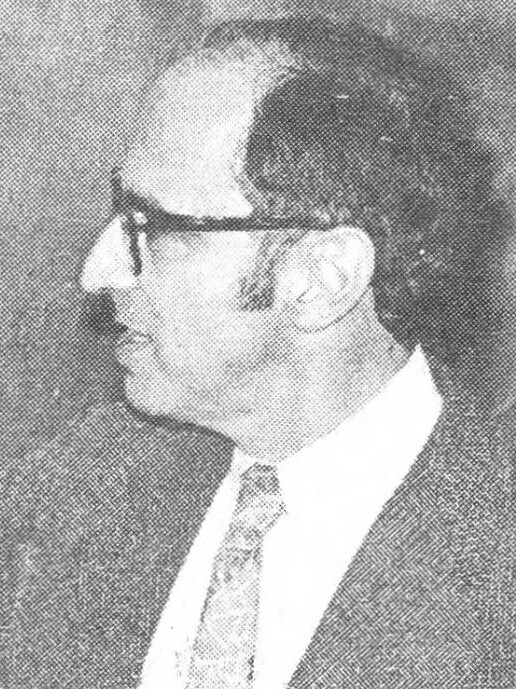 Black-and-white 1977 photo of Thomas Kuhn, a man in glasses and a jacket, drawing on a blackboard.